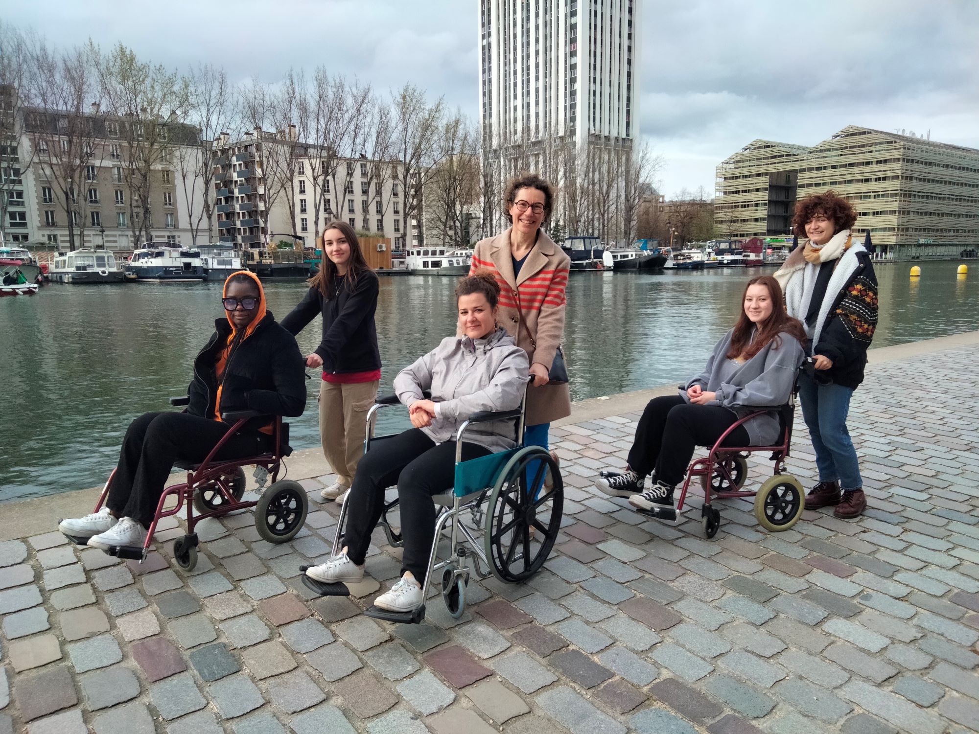 Six jeunes bénévoles de l’association Rhiz’homes ont participé à une balade en fauteuil roulant le long des quais de la Seine. 3 d'entres-eux sont dans des fauteuils tandis que les autres sont leur chauffeurs.